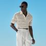 This sand button crochet polo is tailored to a slim fit and features a classic button collar, crochet texture, and ribbed hem and cuffs.