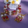 Meer rijen armband met oorbellen in goudkleur met rood en wit.